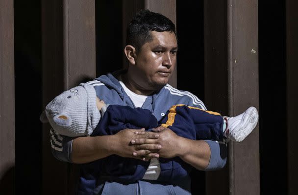 PHOTO: A migrant father holds his son in his arms as he waits to be processed by Border Patrol agents after crossing illegally the border between the United States and Mexico, in Yuma, Ariz., May 10, 2023. (Etienne Laurent/EPA via Shutterstock)