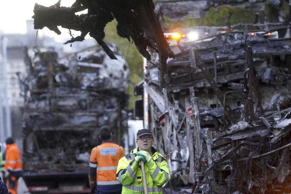 Un trabajador retira escombros el viernes 24 de noviembre 2023 junto a camiones de transporte público quemados en la calle O'Connell, luego de actos de violencia registrados el jueves por la noche en el centro de Dublín. (Brian Lawless/PA vía AP)