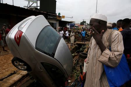 People look at a car in a sewer after a flood in Abidjan, Ivory Coast, June 19, 2018. REUTERS/Luc Gnago