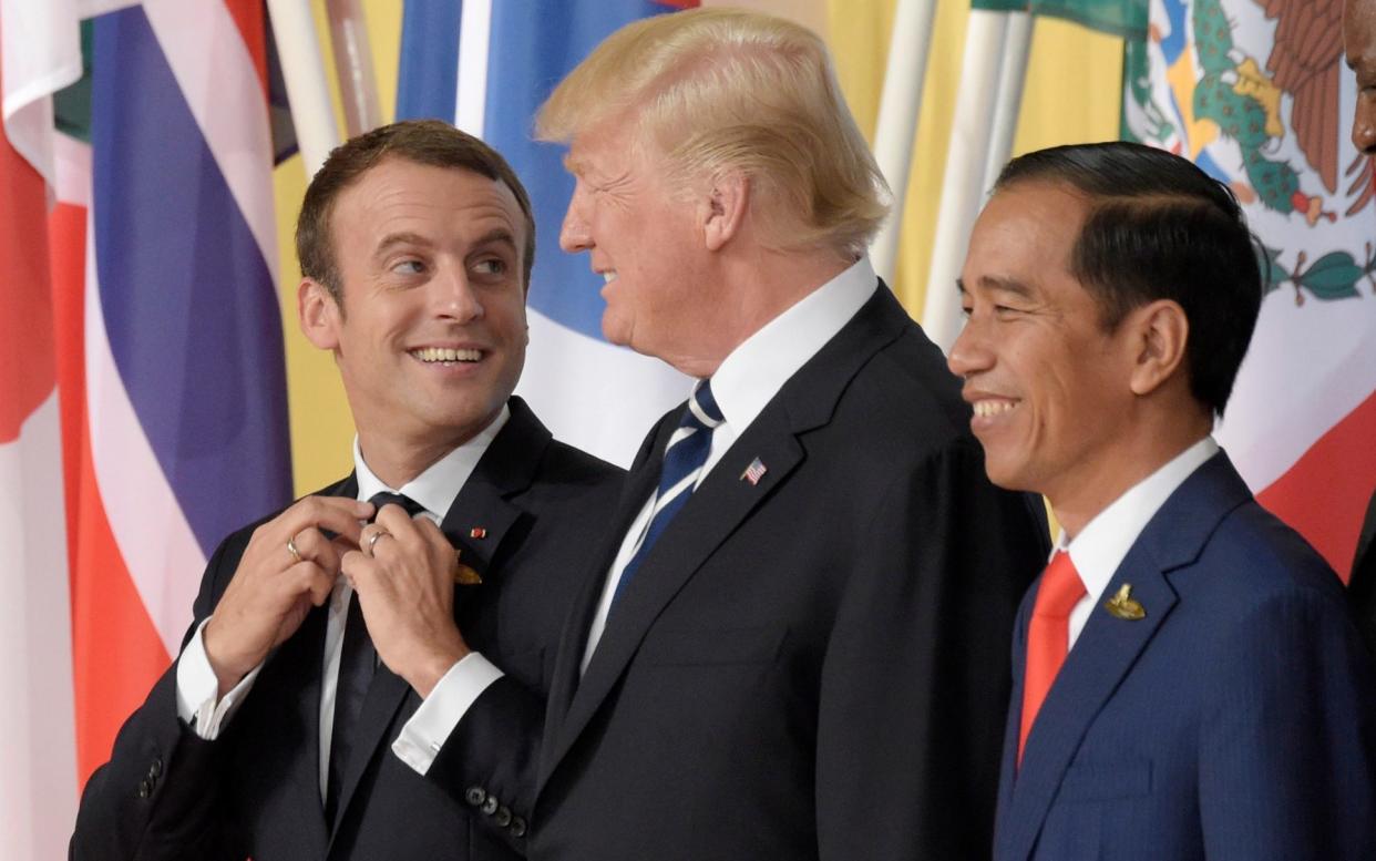 Emmanuel Macron, left, adjusts his tie as he jokes with US President Donald Trump - AP