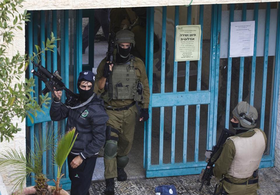 Israeli police officers scan the area near the scene of an attack at a Jerusalem synagogue