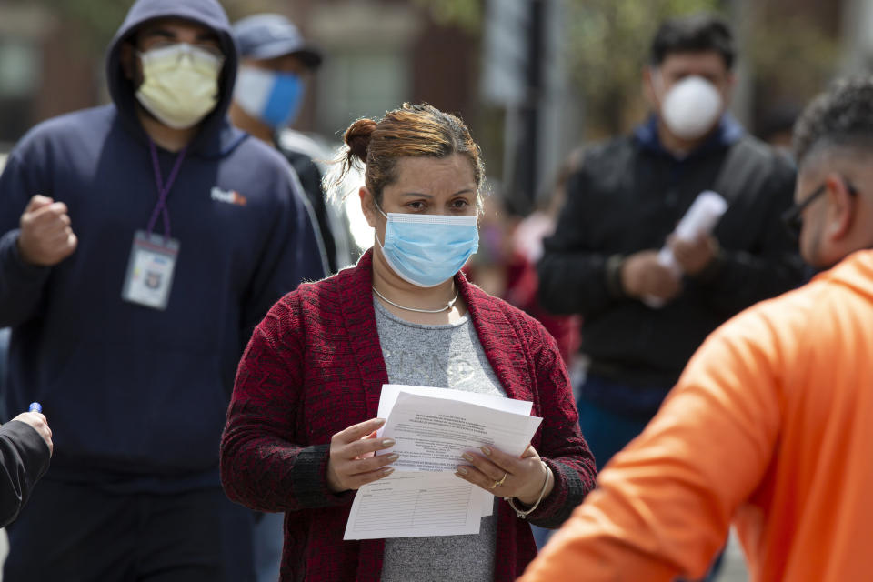 A woman waits to receive food at a distribution site during the coronavirus pandemic, Friday, May 8, 2020, in Chelsea, Mass. (AP Photo/Michael Dwyer)