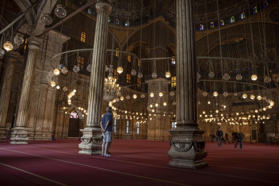 FILE - In this March 18, 2020, file photo, an American tourist looks at the great Mosque of Muhammad Ali Pasha at the Citadel complex, in Cairo, Egypt. Muslims will be grappling during the upcoming Islamic holy month of Ramadan with how to observe familiar rituals in a time of unfamiliarity after the coronavirus has disrupted Islamic worship. (AP Photo/Nariman El-Mofty, File)