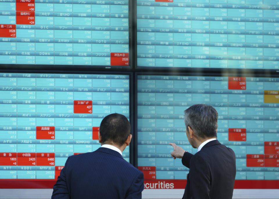 Men look at an electronic stock board showing Japan’s Nikkei 225 index