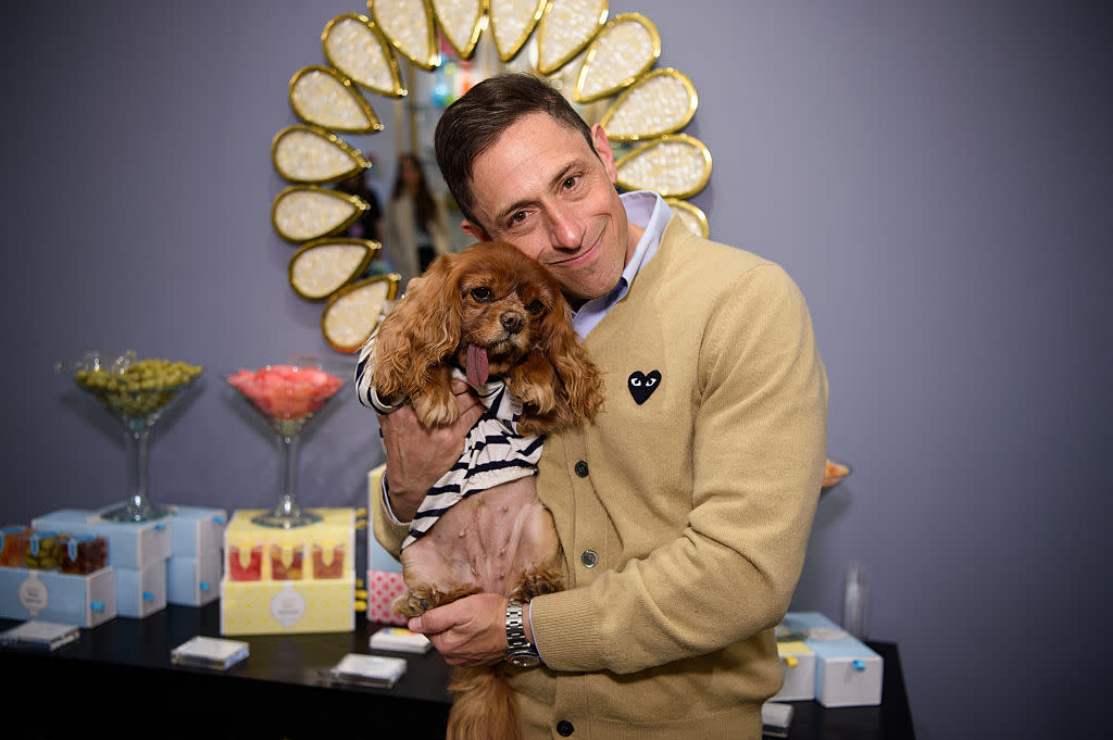  Jonathan Adler holding a dog at an event and smiling. 