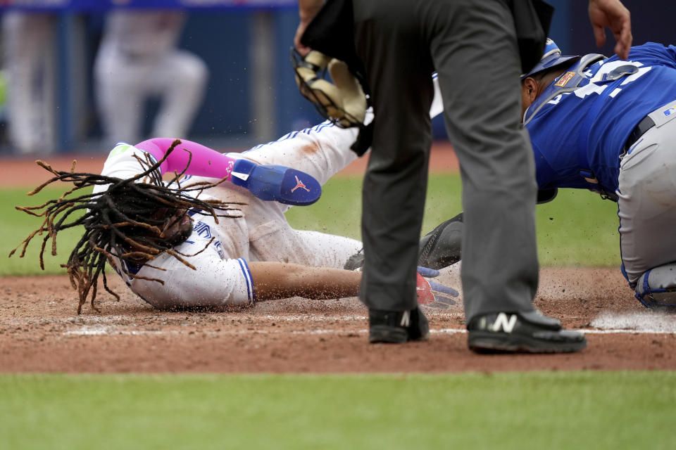 Toronto Blue Jays' Vladimir Guerrero Jr. (27) dives into home plate to score a run as Kansas City Royals catcher Salvador Perez (13) waits for the throw during the sixth inning of a baseball game in Toronto, Saturday, Sept. 9, 2023. (Nathan Denette/The Canadian Press via AP)