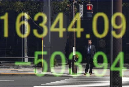 A businessman is reflected in an electronic board displaying Japan's Nikkei share average outside a brokerage in Tokyo, Japan, April 18, 2016. REUTERS/Toru Hanai