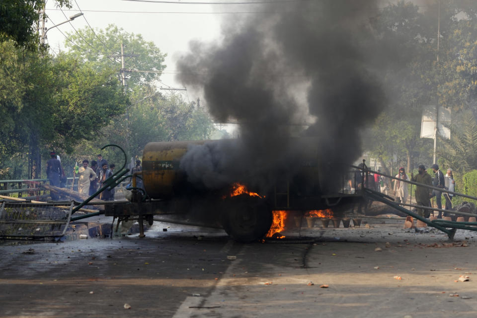 Smoke erupts from a burning water tanker near the site of clashes between supporters of former Prime Minister Imran Khan and riot police officers, in Lahore, Pakistan, Wednesday, March 15, 2023. Clashes between Pakistan's police and supporters of Khan persisted outside his home in the eastern city of Lahore on Wednesday, a day after officers went to arrest him for failing to appear in court on graft charges. (AP Photo/K.M. Chaudary)