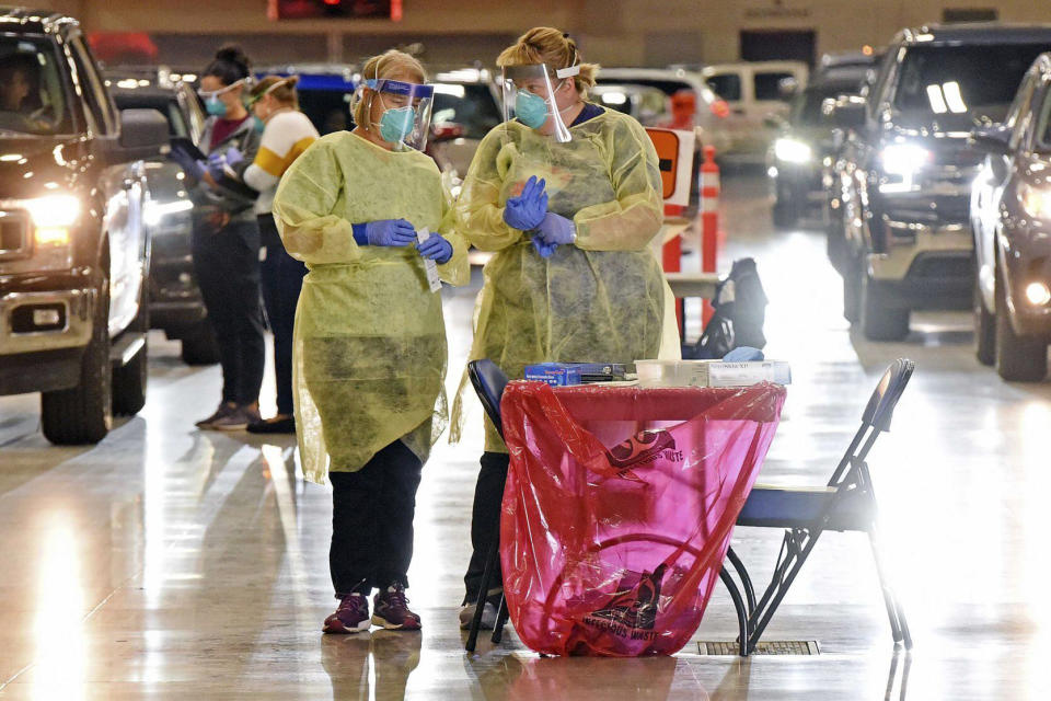 FILE - In this Sept. 8, 2020, file photo, Bismarck-Burleigh Public Health nurses Crys Kuntz, left, and Sara Nelson confer inside the Bismarck Event Center in Bismarck, N.D., where vehicles were lined up for the weekly drive-thru COVID-19 testing. The coronavirus tightened its grip on the American heartland, with hospitals in Wisconsin and North Dakota running low on space, and the NFL postponing a game over an outbreak that's hit the Tennessee Titans football team. (Tom Stromme/The Bismarck Tribune via AP, File)