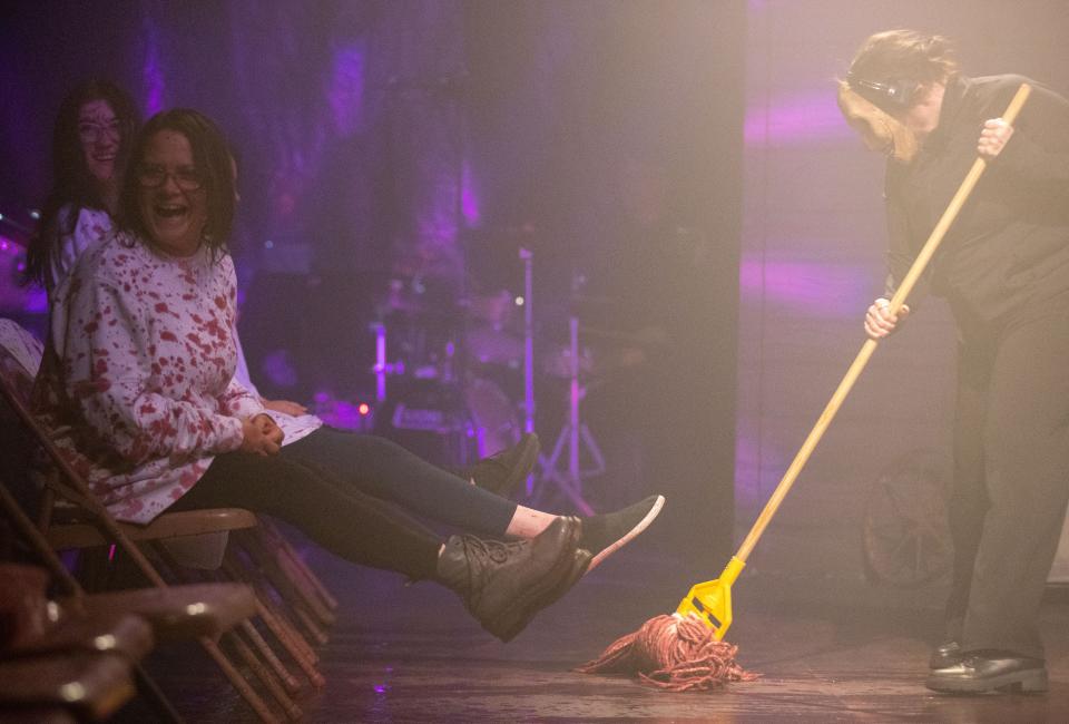 Kathy Jacobson lifts her feet as a cast member mops up fake blood during “Evil Dead The Musical” on Thursday, Oct. 27, 2022, at Theatreworks On The Square in Memphis. Jacobson wore an outfit she plans to now use as her Halloween costume.