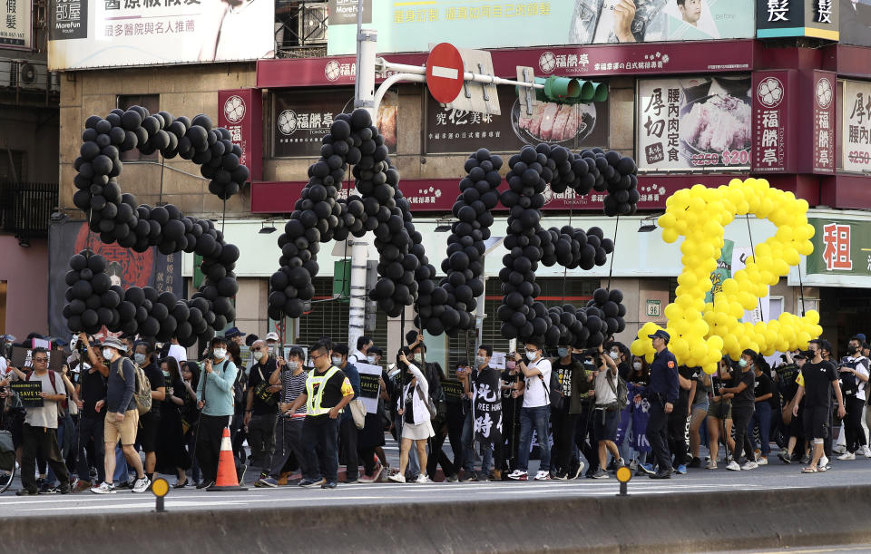 Hong Kong protesters and Taiwanese supporters march to demand the release of the 12 Hong Kong protesters that have been arrested by mainland Chinese authorities, in Taipei, Taiwan, Sunday, Oct. 25, 2020. A group of 12 people from Hong Kong were allegedly traveling illegally by boat to Taiwan in August when Chinese authorities captured them and detained them.(AP Photo/Chiang Ying-ying)