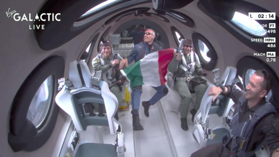 Italian crew members of Virgin Galactic's Galactic 01 flight hold up the Italian flag while experiencing the weightlessness of space.