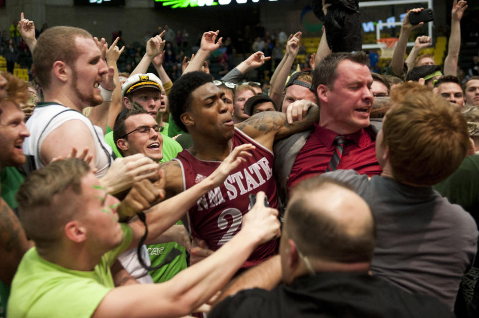 In this Thursday, Feb. 27, 2014 photo, New Mexico State's Daniel Mullings, center left in red and white jersey, is involved in a brawl involving players and fans who came onto the court when New Mexico State guard K.C. Ross-Miller hurled the ball at Utah Valley's Holton Hunsaker seconds after the Wolverines' 66-61 overtime victory against the Aggies in Orem, Utah. (AP Photo/The Daily Herald, Grant Hindsley) MANDATORY CREDIT