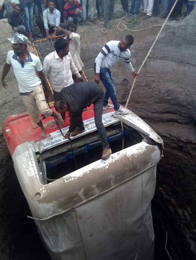 Rescuers pull the bus out of a well