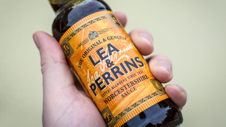 Hand holding jar of Worcestershire sauce