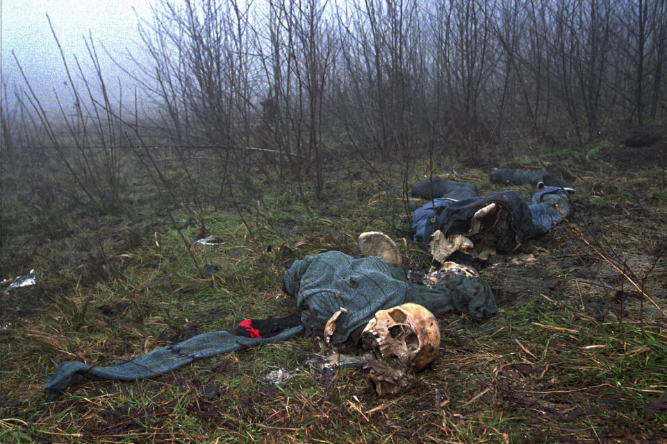 FILE - In this Feb. 4, 1996, file photo one of four clothed skeletons being examined by U.N. investigator Elizabeth Rehn as she tries identify an estimated 8,000 Muslim men missing after the Serb conquest of the former Muslim enclave of Srebrenica in July 1995, lies on a hilltop. Twenty-six years after the July 1995 Srebrenica massacre, the only episode of Bosnia’s 1992-95 war to be legally defined as genocide, its survivors continue to grapple with the horrors they endured while also confronting increasingly aggressive downplaying and even denial of their ordeal. (AP Photo/Alexander Zemlianichenko, File)