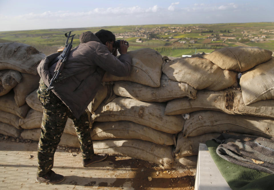 FILE -- In this March 29, 2018 file photo, a fighter from the U.S-backed Syrian Manbij Military Council looks through his binoculars to Turkish-backed fighters' positions, at the front line of Halawanji village, north of Manbij, Syria. Sharfan Darwish, spokesman of the Manbij Military Council,w said Thursday Nov. 1, 2018, that joint U.S.-Turkish patrols will begin within hours around the northern Syrian town of Manbij, part of a roadmap for easing tensions between the two NATO allies. Ankara and Washington agreed on a roadmap in June amid Turkish demands for the withdrawal of the U.S.-backed Kurdish militia that freed Manbij from the Islamic State group in 2016. (AP Photo/Hussein Malla, File)