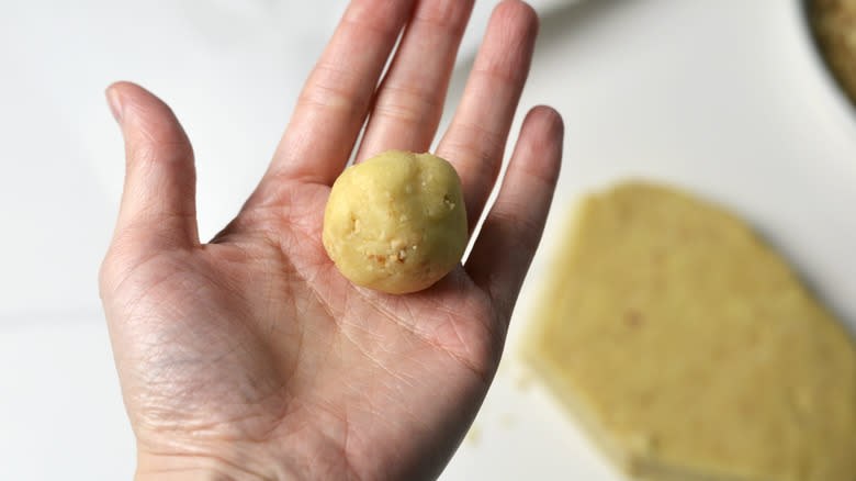 Hazelnut thumbprint cookie dough balls in the palm of a hand