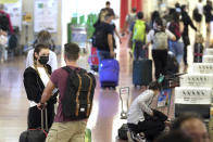 Foreign travelers walk upon arrival at the Haneda International Airport Tuesday, Oct. 11, 2022, in Tokyo. Japan's strict border restrictions are eased, allowing tourists to easily enter for the first time since the start of the COVID-19 pandemic. Independent tourists are again welcomed, not just those traveling with authorized groups. (AP Photo/Eugene Hoshiko)