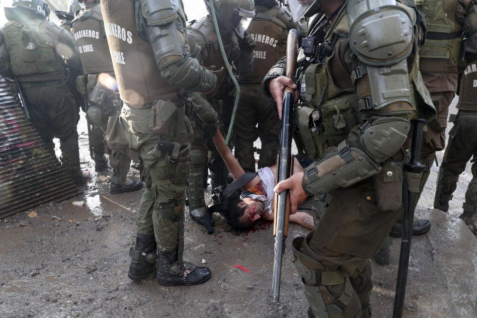 Police stand around an anti-government protester injured during clashes in Santiago, Chile, Thursday, Nov. 14, 2019. Students in Chile began protesting nearly a month ago over a subway fare hike. The demonstrations have morphed into a massive protest movement demanding improvements in basic services and benefits, including pensions, health, and education. (AP Photo/Esteban Felix)