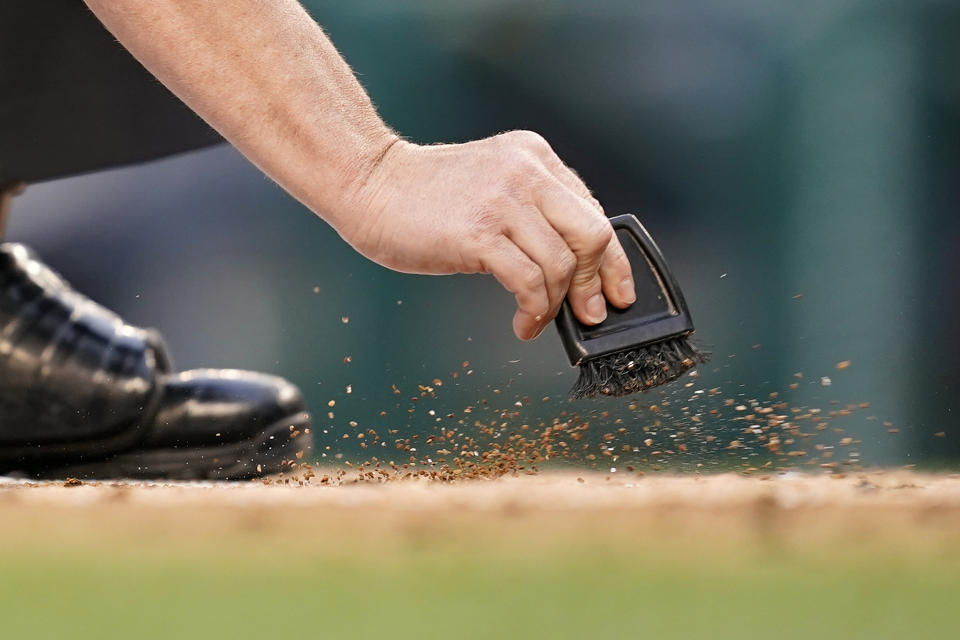 Home plate umpire Sean Barber sweeps dirt from home plate in the first inning of a baseball game between the Colorado Rockies and the Washington Nationals, Thursday, May 26, 2022, in Washington. (AP Photo/Patrick Semansky)