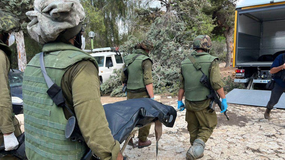 Soldados israelíes trasladan cadáveres en el kibutz de Kfar Aza.