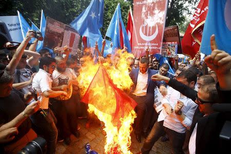 Demonstrators set fire to a Chinese flag during a protest against China near the Chinese Consulate in Istanbul, Turkey, July 5, 2015. REUTERS/Osman Orsal