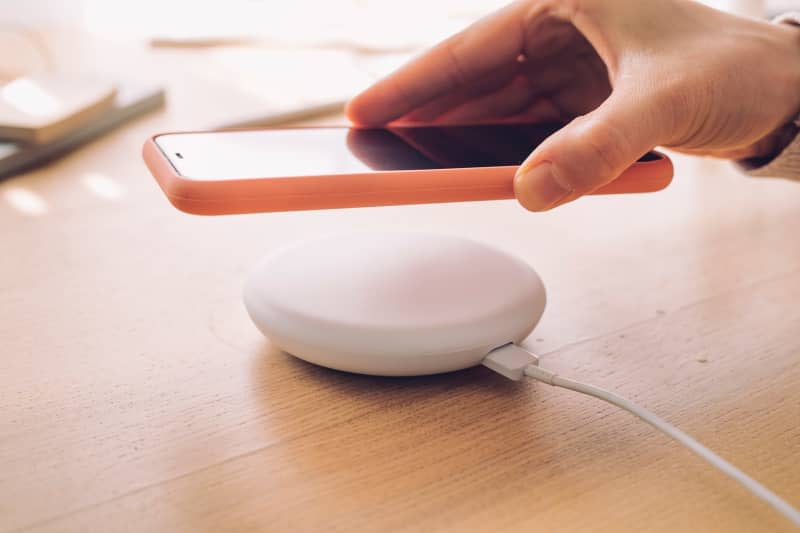 Wireless charging: a mobile phone being placed on a modern wireless power bank.