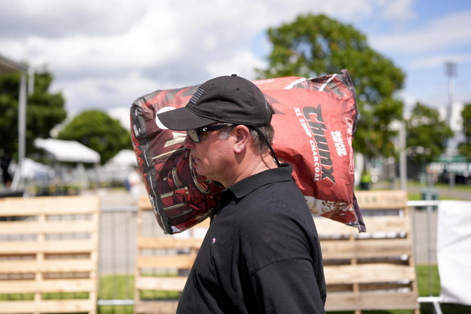 Randy Pirtle, of the Swinefeld barbecue team, carries a bag of charcoal at the World Championship Barbecue Cooking Contest, Friday, May 17, 2024, in Memphis, Tenn. (AP Photo/George Walker IV)