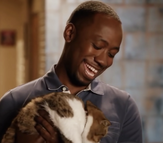 a man smiling down as he holds his cat