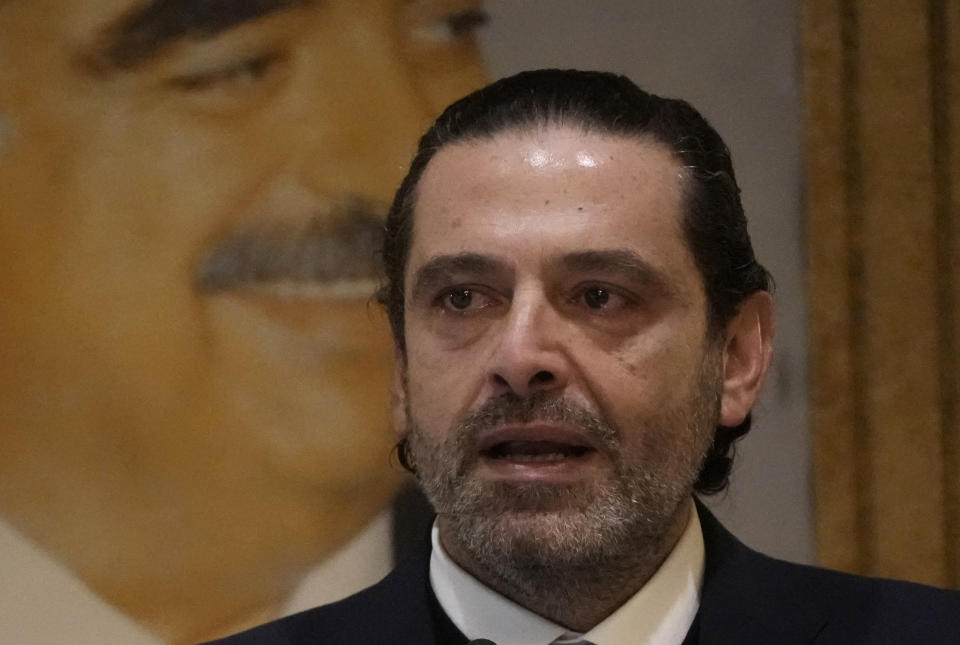 Former Lebanese Prime Minister Saad Hariri holds back tears as he gives a speech, in front of a picture of his late father and former Prime Minister of Lebanon Rafic Hariri, at his house in downtown Beirut, Lebanon, Monday, Jan. 24, 2022. Hariri said Monday he is suspending his work in politics and will not run in May's parliamentary elections. (AP Photo/Hussein Malla)