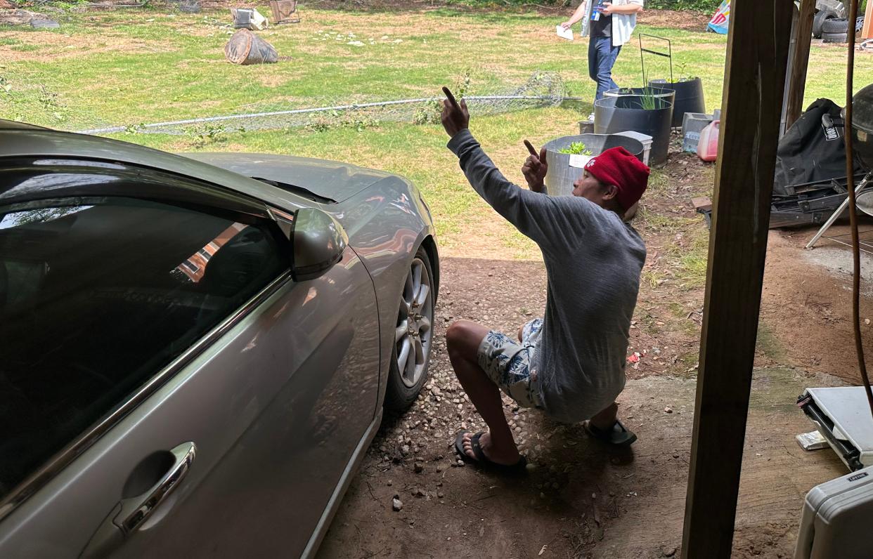 Saing Chhoeun, 54, shows how an officer took cover behind a sedan parked in his driveway and fired at the house next door during an incident April 29, 2024, in Charlotte, N.C., where four law enforcement officers, including three on a U.S. Marshals Task Force, were killed and four other officers were injured after being shot while attempting to serve a warrant.