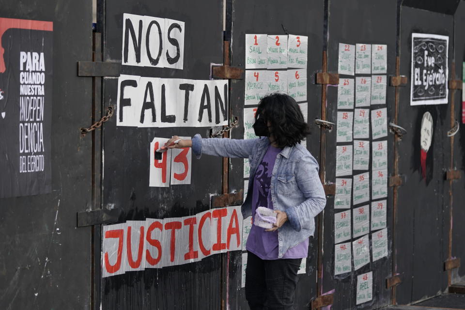 A youth paints "We are missing 43. Justice," on a police barricade placed in front of the National Palace during a march for the missing 43 Ayotzinapa college students in Mexico City, Monday, Sept. 26, 2022, on the day of the anniversary of the disappearance of the students in Iguala, Guerrero state. Three members of the military and a former federal attorney general were recently arrested in the case, and few now believe the government's initial claim that a local drug gang and allied local officials were wholly to blame for seizing and killing the students on July 26, 2014, most of which have never been found. (AP Photo/Eduardo Verdugo)