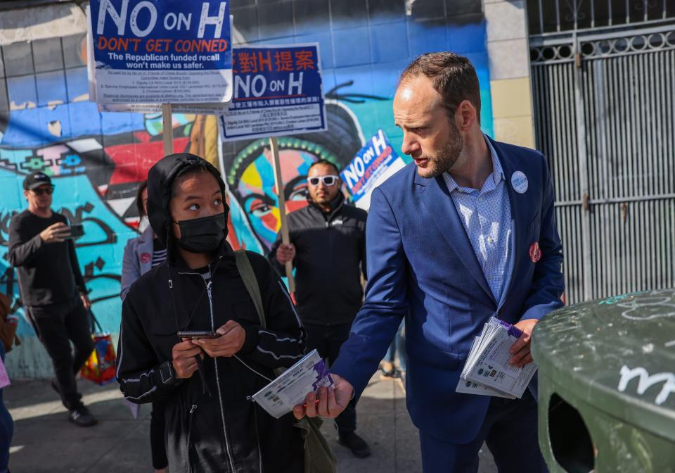 District Attorney Chesa Boudin hands out fliers in the Mission District on Tuesday, June 7, 2022, in San Francisco. City Supervisor Hillary Ronen is drafting a resolution that would urge state legislators to write a bill that would legalize sex work. Mission residents want the now-illicit business plaguing part of the neighborhood contained in a commercial zone.