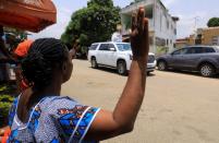A woman raises her arms as Abbe Abekan travels around the streets praying to stop the spread of coronavirus disease (COVID-19), in Abidjan