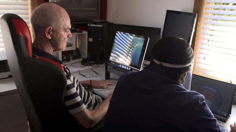 man with brain computer interface sits at computer - hands on desk, controlling it with his mind