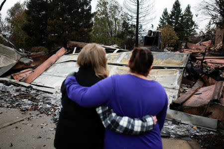 Irma Corona (R) comforts neighbor Gerryann Wulbern in front of the remains of Wulbern's home after the two returned for the first time since the Camp Fire in Paradise, California, U.S. November 22, 2018. REUTERS/Elijah Nouvelage/File Photo