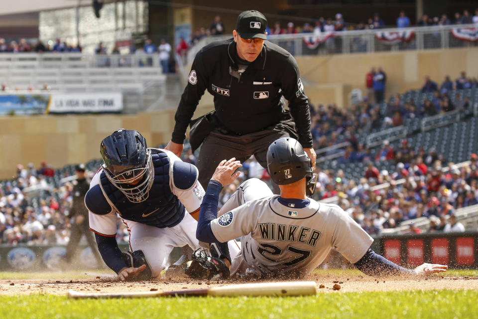 Seattle Mariners' Jesse Winker (27) is tagged out at home after attempting to score from first against the Minnesota Twins during the first inning of a baseball game, Sunday, April 10, 2022, in Minneapolis. (AP Photo/Nicole Neri)