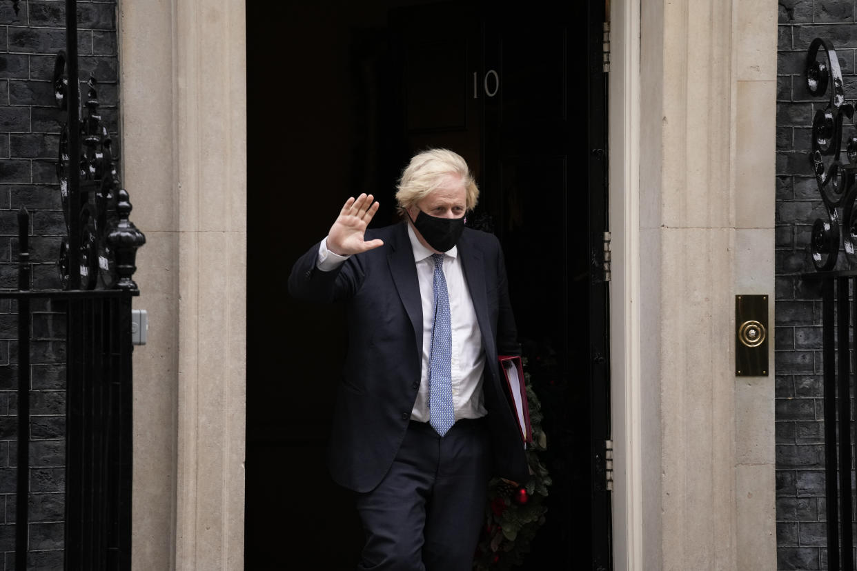 British Prime Minister Boris Johnson waves at the media as he leaves 10 Downing Street to attend the weekly Prime Minister's Questions at the Houses of Parliament, in London, Wednesday, Dec. 8, 2021. (AP Photo/Matt Dunham)