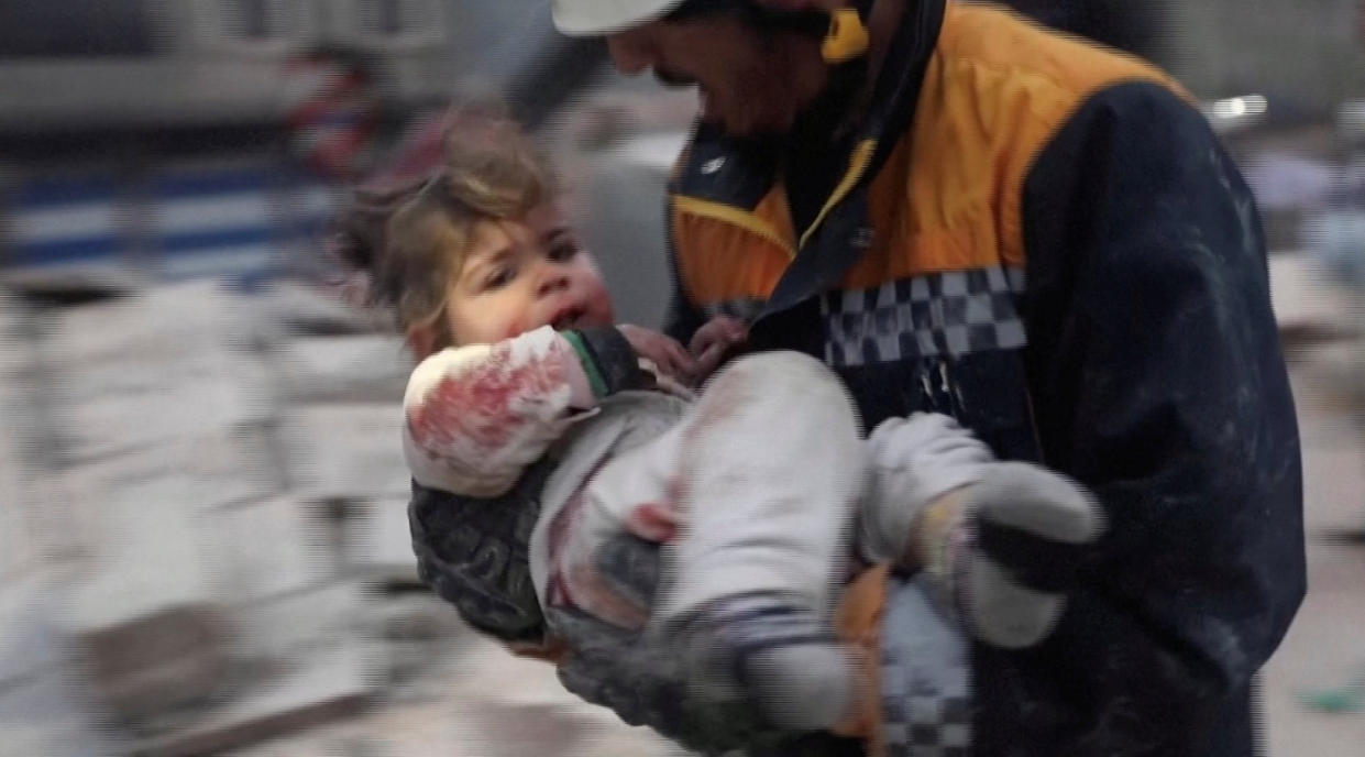 A rescuer carries an injured child following an earthquake in Azaz, Syria.