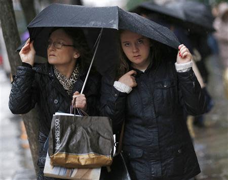 Pedestrians walk in wet and windy weather on Oxford Street in central London December 23, 2013. REUTERS/Olivia Harris