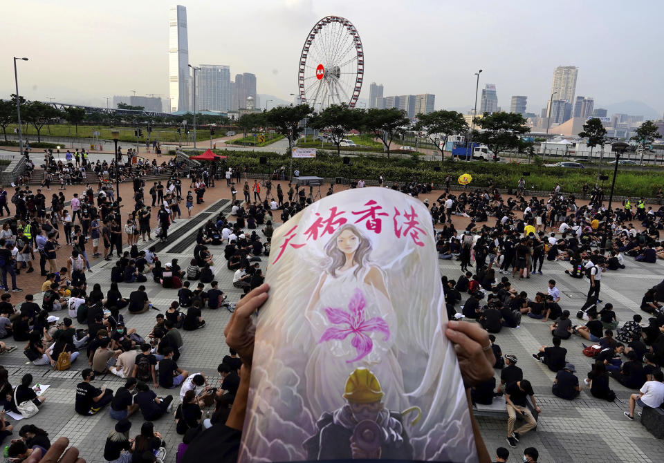 A protestor holds a sign reading "God bless Hong Kong" during a demonstration by students and others at Edinburgh Place in Hong Kong, Thursday, Aug. 22, 2019. High school students thronged a square in downtown Hong Kong Thursday to debate political reforms as residents gird for further anti-government protests. (AP Photo/Vincent Yu)