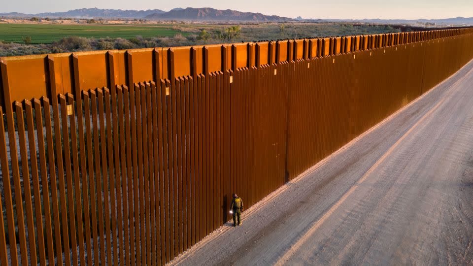 In an aerial view, a US Border Patrol agent searches for immigrant footprints while looking through the US-Mexico border fence on March 9, in Yuma, Arizona. - John Moore/Getty Images