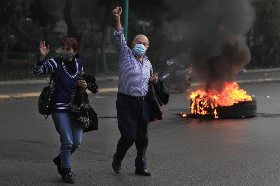 FILE - Residents raise their hands as they cross a street during a protest against rising prices of consumer goods and the crash of local currency in Beirut, Lebanon, Monday, Nov. 29, 2021. Some 1.6 billion people in 94 countries face at least one dimension of the crisis in food, energy and financial systems, according to a report last month by the Global Crisis Response Group of the United Nations Secretary-General. (AP Photo/Hussein Malla, File)