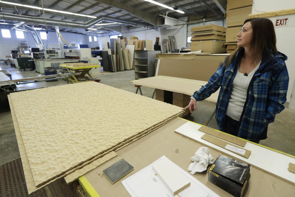 In this Nov. 20, 2019 photo, Jamie Cline pauses while passing through a cabinet-making area at Genothen, a millwork shop where she is employed in Tumwater, Wash. Cline, who in the past had used heroin for ten years, got the job and cleaned up other areas of her life once she started taking a prescription medication called buprenorphine that she got at a clinic in Olympia, Wash., where a doctor is working to spread a philosophy called "medication first." The surprising approach scraps requirements for counseling, abstinence or even a commitment to recovery. (AP Photo/Ted S. Warren)