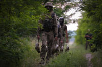 A Ukraine special operations unit carries anti-tank mines to bury on a forest track to prevent Russian troops from advancing toward their trenches, in the Donetsk region, Ukraine,Tuesday, June 14, 2022. (AP Photo/Efrem Lukatsky)