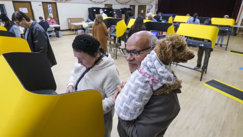 Feel Flores, 67, holds his dog Lulu as he waits for his wife Ana Marina, 67, to cast her ballot at a vote station on Nov. 8, 2022, in Los Angeles.