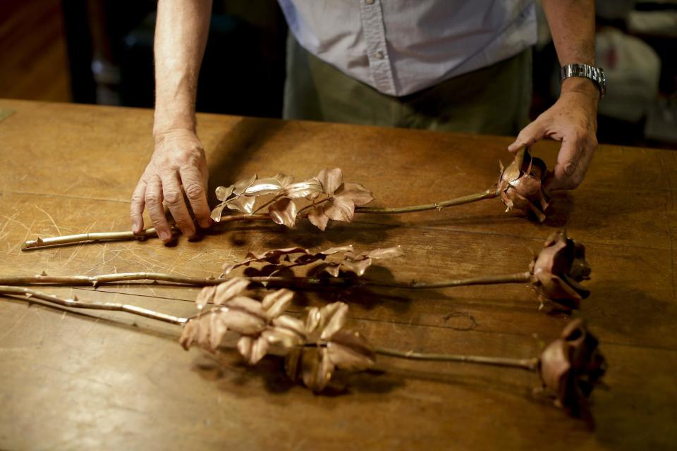 Juan Carlos Pallarols places roses he made with spent munitions from the Falklands war on a desk at his studio in Buenos Aires, Argentina, Wednesday, Jan. 25, 2017. The 74-year-old Argentine goldsmith known for crafting the presidential batons, collects old ammunition from the 1982 Falklands war to craft roses which he will send to the Argentine and British war cemeteries on the islands in an effort to build a bridge of peace and understanding between the nations. (AP Photo/Victor R. Caivano)