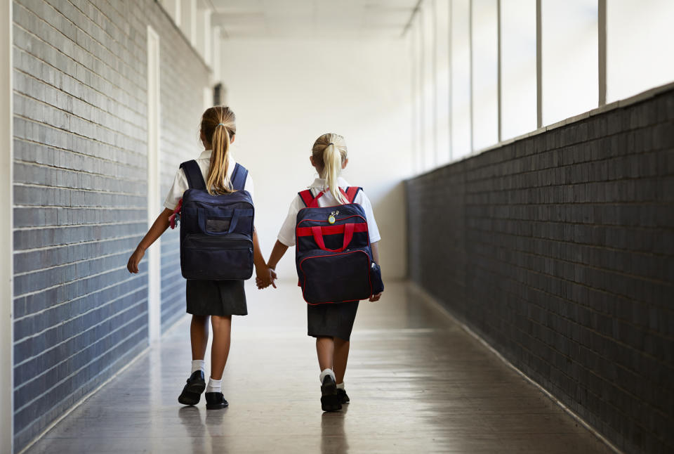 Schoolgirls walking hand in hand at school.