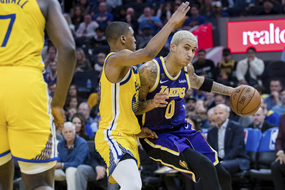 Los Angeles Lakers forward Kyle Kuzma (0) dribbles as Golden State Warriors guard Andrew Wiggins, left, defends in the first half of an NBA basketball game in San Francisco Saturday, Feb. 8, 2020. (AP Photo/John Hefti)